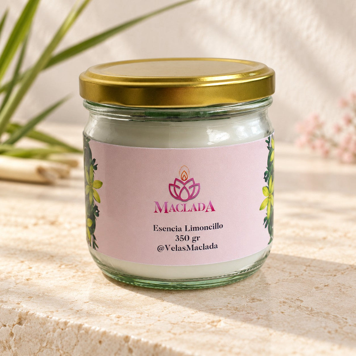Vela artesanal de limoncillo MACLADA, de 350 g, en una ambientación clara con hojas de limoncillo.